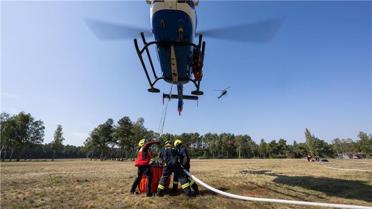 Feuerwehren üben Einsatz mit Hubschrauber Geübt wurde unter anderem einen Behälter unter einem Helikopter im Schwebeflug mithilfe eines Füllrohrs mit Löschwasser zu füllen.