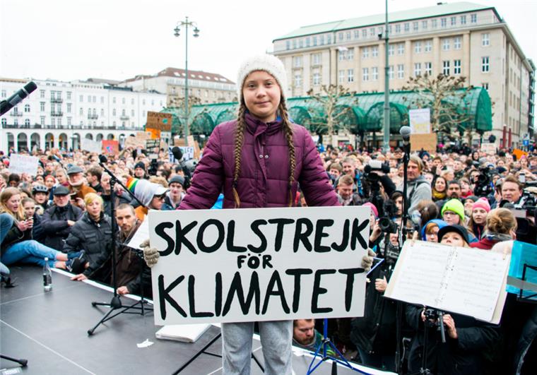 Greta Thunberg, Klimaaktivistin, steht während einer Kundgebung in Hamburg auf dem Rathausmarkt mit einem Transparent auf einer Bühne. Die junge Schwedin ist erstmals für einen Schulstreik für mehr Klimaschutz nach Deutschland gekommen.