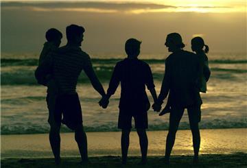 Eine Familie mit Kindern am Strand, Silhouette. Große Familien bekommen ab 2025 deutlich mehr Kindergeld. Doch nicht alle sind zufrieden – Reformen stehen weiter im Raum.