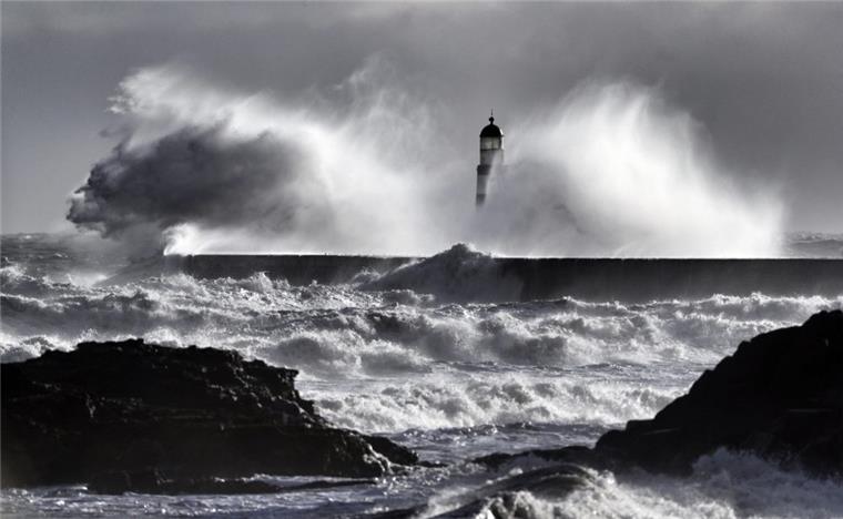 Große Wellen stürzen bei kaltem Wetter über einen Leuchtturm in Großbritannien.