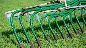Gülle als organisches Düngemittel von einem Traktor mit Schleppschlauchverteiler ausgebracht.