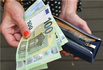 Eine Frau hält mehrere 100-Euro-Scheine und eine Geldbörse in der Hand. Ende März bekommen Millionen Haushalte rund 300 Euro ausgezahlt.