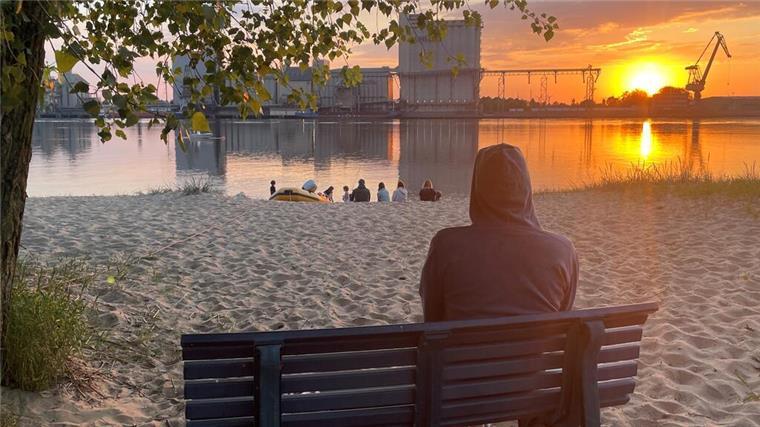 Eine Person beobachtet den Sonnenuntergang auf Harriersand. Wir zeigen, warum sich ein Besuch auf der Insel lohnt.