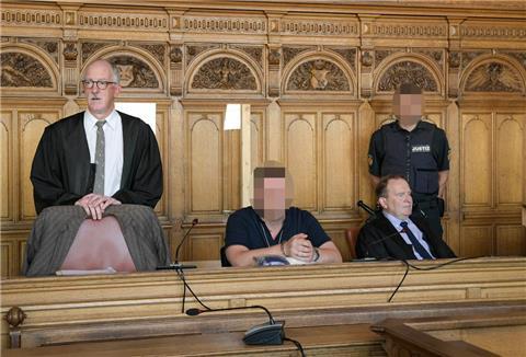 Vier Männer befinden sich in einem Gerichtssaal. Bei zwei Männern ist das Gesicht unkenntlich gemacht worden.