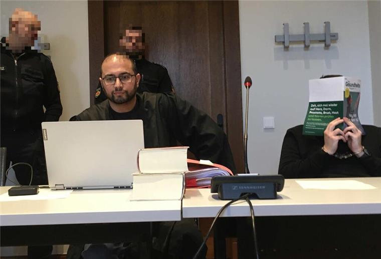 Angeklagter neben seinem Anwalt und den Justizbeamten