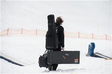 Heavy Metal - schweres Gepäck: Ein Musiker trägt   im Ski-Gebiet Nassfeld in Österreich während des "Full Metal Mountain" Festivals Gitarren zur Tresdorfer Alm.