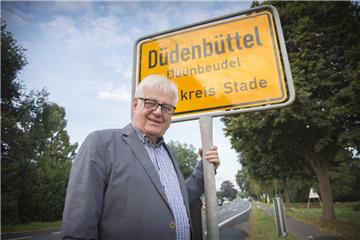 Heinz Muegge, Bürgermeister der Gemeinde Duedenbuettel, steht vor einem von ihm initiierten zweisprachigen Ortsschild. Mittlerweile haben über 60 Orte Tafeln in Hoch- und Plattdeutsch aufgestellt.