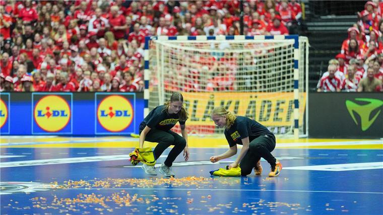 Protest bei Handball-WM: Trainer schubst Störer vom Feld Helfer entfernen Konfetti, das ein Mann zuvor auf dem Handball-Feld verstreut hatte.