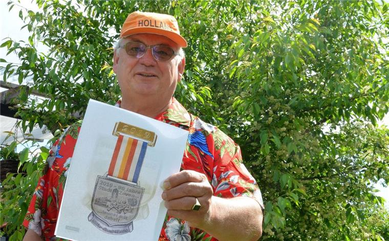Tradition aus Holland: Vier-Abend-Märsche in Zeven starten Montag Henk Tijink, Moderator und Mit-Organisator der Vier-Abend-Märsche in Zeven, schreckt vor schrillen Outfits nicht zurück, um der Veranstaltung Aufmerksamkeit zu sichern. Hier zeigt er ein Bild der Medaille, die die Teilnehmer bekommen, die an mindestens drei der vier Abende mitlaufen.