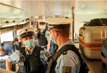 Polizisten mit Gesichtsmasken in einem Zug.