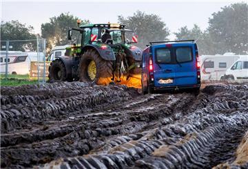 Autos werden mit Hilfe eines Traktors auf das Gelände des Heavy-Metal-Festivals in Wacken durch den Schlamm gezogen.