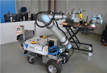 Mobiler Roboter mit Greifarm vom Fraunhofer CML und Innok Robotics bei einer Vorführung in einem Laborraum.