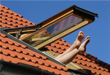 Eine Wohnung im Dachgeschoss mit offenem Fenster. Füße schauen heraus.