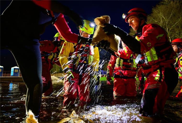 Strömungsretter der DLRG sichern beim Weihnachtshochwasser um den Jahreswechsel 2023/2024 mit Sandsäcken einen Deich. (zu dpa: «Mehr Hilfe für die Helfer»)