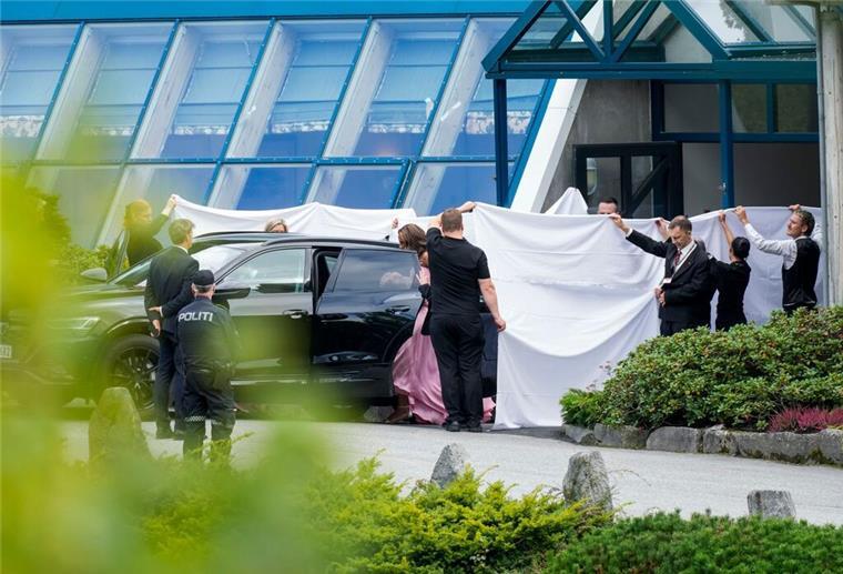 Hotelangestellte schirmen das Brautpaar vor Blicken ab.