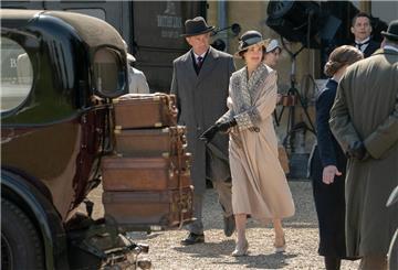 Ein Mann und eine Frau neben einem Oldtimer. Die Kult-Serie Downton Abbey kommt zurück. Jetzt ist die richtige Zeit, einen privaten Serien-Marathon zu starten.