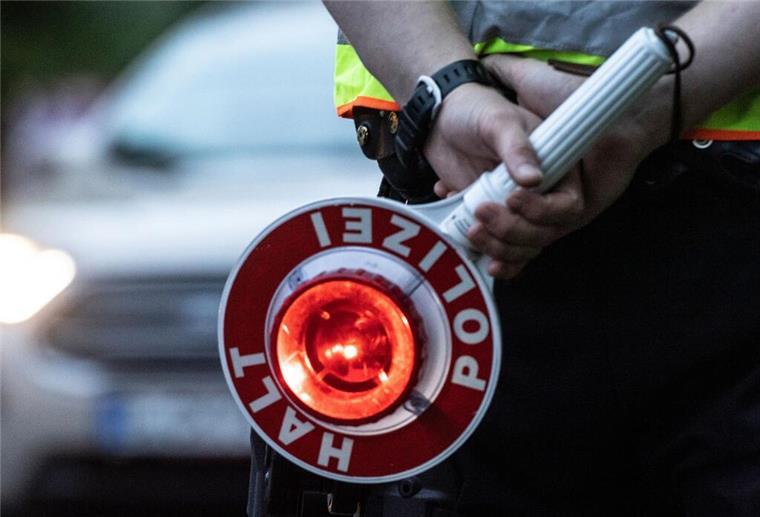 Ein Polizist hält bei einer Verkehrskontrolle eine Winkerkelle in der Hand