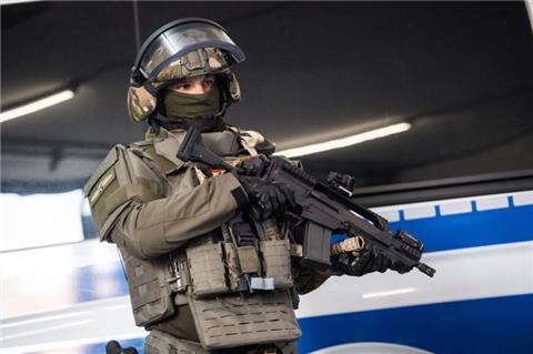 Ein SEK-Beamter steht mit seiner neuen Ausrüstung vor einem Polizeifahrzeug.