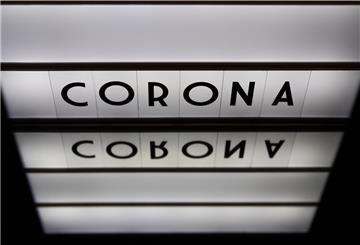 Ein Leuchtkasten mit den Worten Corona, Covid-19, 2020 spiegelt sich in einem Spiegel. (gestellte Szene