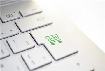 Weiße Computertastatur mit grünem Shoppingcart-Button.