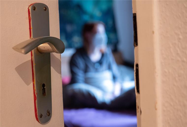 Eine Frau sitzt während der Isolation nach einem positiven Corona-PCR-Test auf ihrem Bett