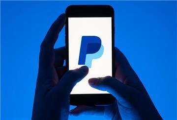 Eine Frau hält ein Smartphone mit dem Logo des Bezahldienst Paypal.