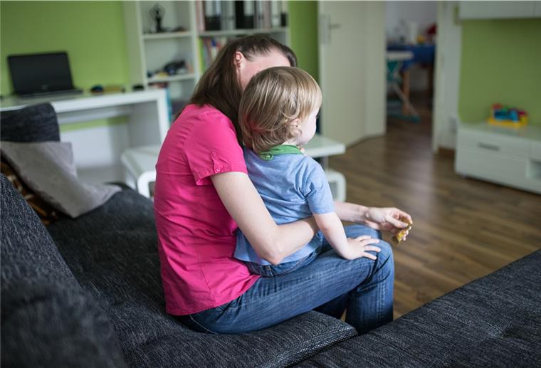 Eine Mutter sitzt mit ihrem Sohn auf dem Schoß auf einer Couch. 
