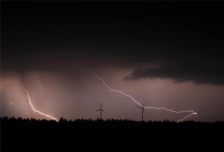 Blitze entladen sich hinter zwei Windrädern. +++ dpa-Bildfunk +++
