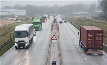 Im östlichen Teil der Cherbourger Straße (Aufnahme vom 05.02.2016) wird die Mittelinsel zwischen den Fahrspuren entfernt, damit der Verkehr dort umgeleitet werden kann, um Platz zu schaffen für den Einbau eines neuen Abwasserkanals, der die Hafenzufahrt unterquert. Links im Hintergrund, am Rand der künftigen Tunneltrasse, liegen bereits einige Kanalbauelemente.