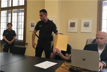 Angeklagter mit Mappe vor dem Gesicht