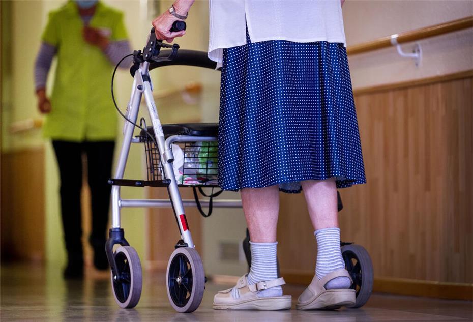 Eine ältere Dame geht mit ihrem Rollator über einen Flur.