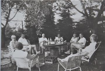 Männer und Frauen sitzen im Sommer 1986 in einem Garten um einen Tisch.