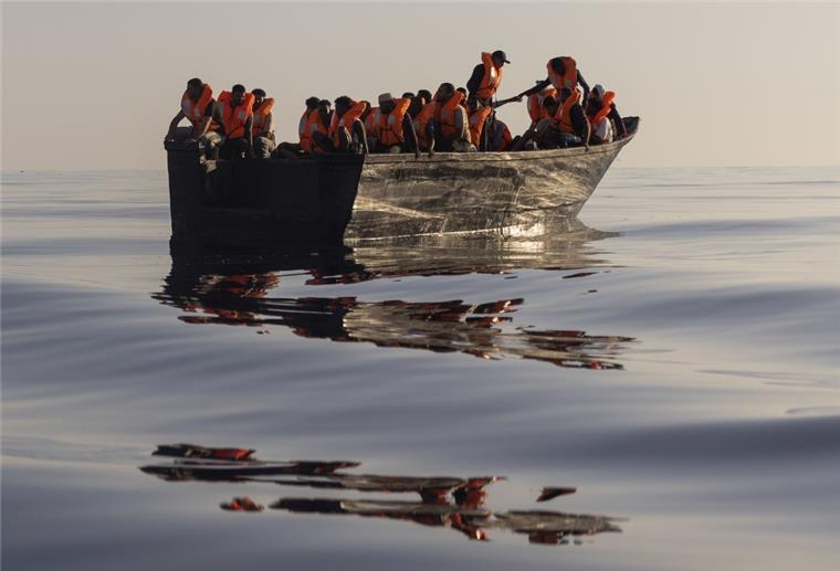Migranten mit Schwimmwesten, die von Freiwilligen des Rettungsschiffs Ocean Viking zur Verfügung gestellt wurden, segeln in einem Holzboot, während einer Rettungsaktion im Mittelmeer. 