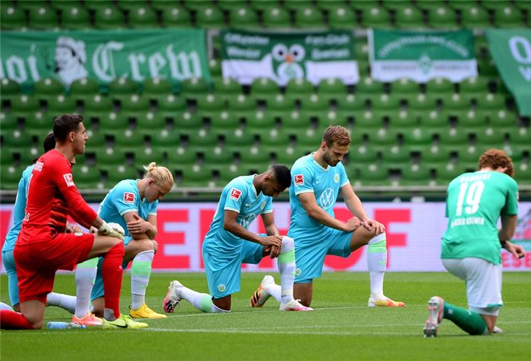 Im Weserstadion: Spieler aus Bremen und Wolfsburg knien gemeinsam auf dem Rasen am Mittelkreis, um ein Zeichen gegen Rassismus zu setzen.