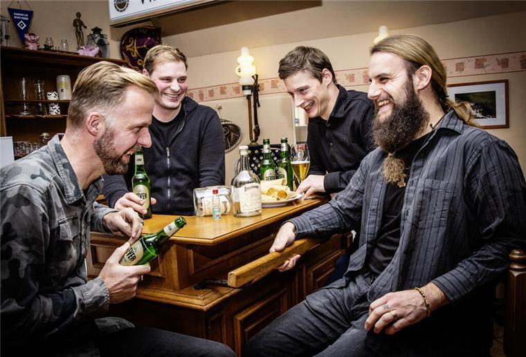 Vier Männer sitzen an einem Tisch und lachen