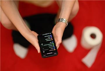 Eine Junge hält auf der Toilette sein Smartphone in den Händen.
