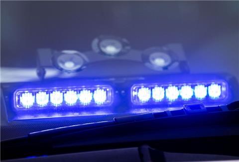 Ein Blaulicht leuchtet unter der Frontscheibe eines Einsatzfahrzeugs der Polizei.