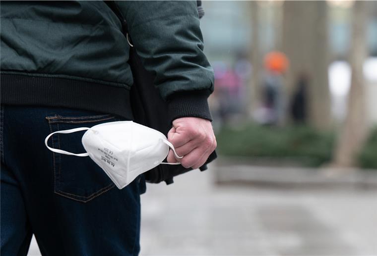 Ein Mann trägt auf der Einkaufsstraße Prager Straße eine FFP-2-Maske in der Hand.