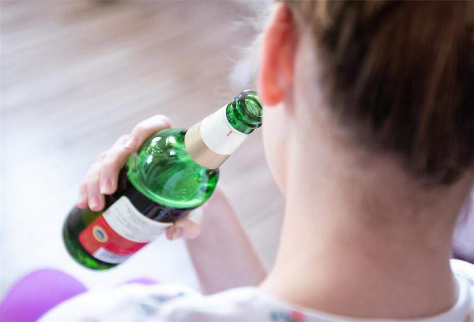 Ein Mädchen hält eine Flasche Bier
