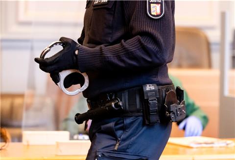 Ein Justizbeamter verlässt mit Handschellen den Platz des Angeklagten ab.