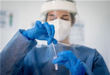Medizinisch geschultes Personal legt das Wattestäbchen nach dem Abstrich für einen Corona-Schnelltest in eine Lösung.