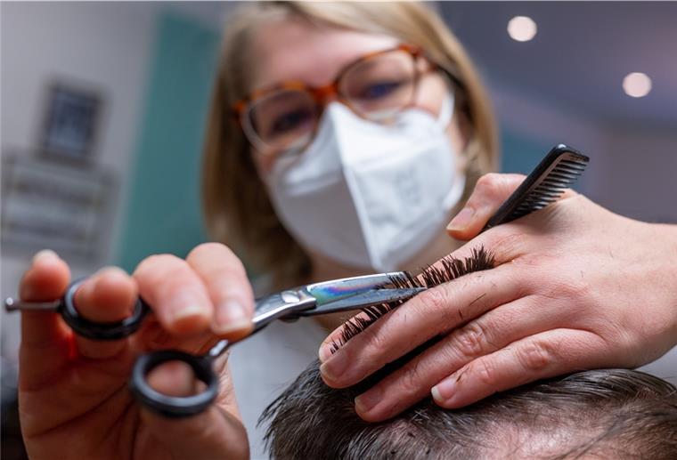 Eine Friseurin schneidet die Haare eines Kunden. 