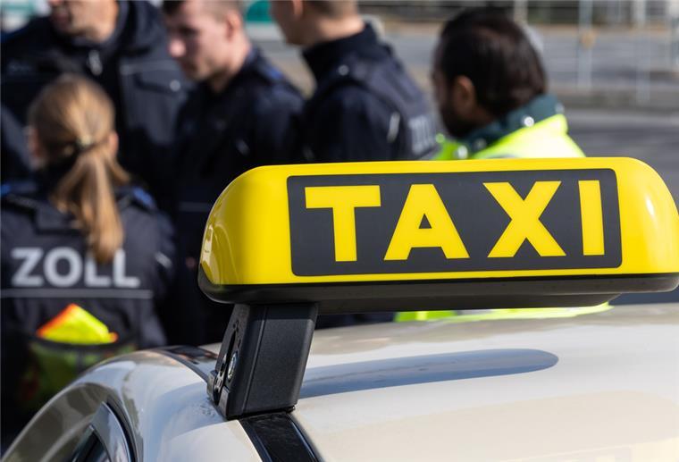 Zollmitarbeiter kontrollieren Taxifahrer.