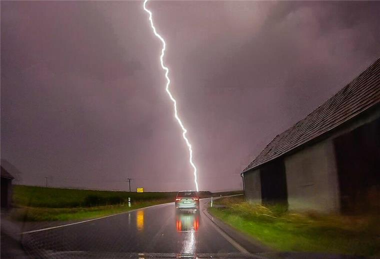  Ein Blitz ist am Himmel hinter einer Straße zu sehen. 