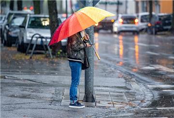 Ein Mann steht während einem Regenschauer mit einem bunten Regenschirm an einer Kreuzung. Für diesen Mittwoch werden im Freistaat Regen- und Gewitterschauer erwartet.