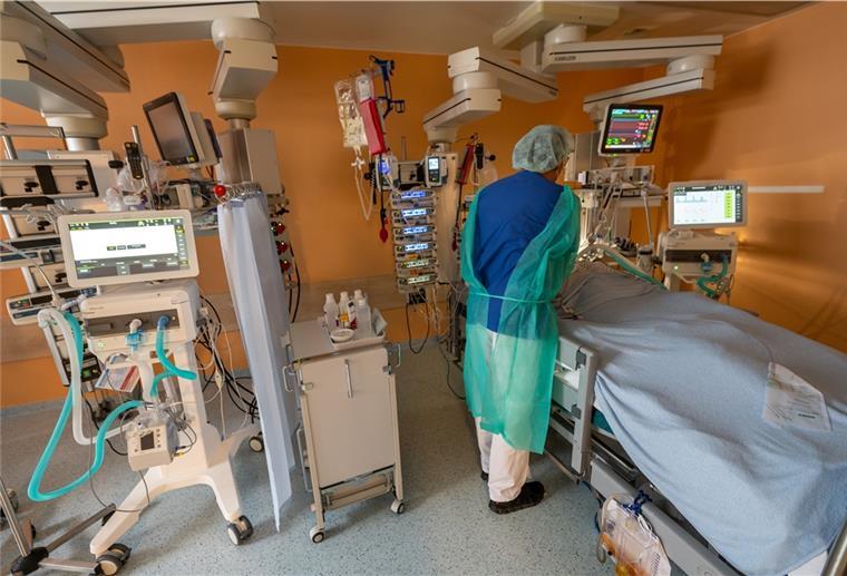 Chefarzt Lorenz Nowak untersucht in Schutzkleidung in einem Intensivbett-Zimmer in der Asklepios Klinik einen geheilten Corona-Patienten, der von der Beatmungsmaschine entwöhnt werden muss.