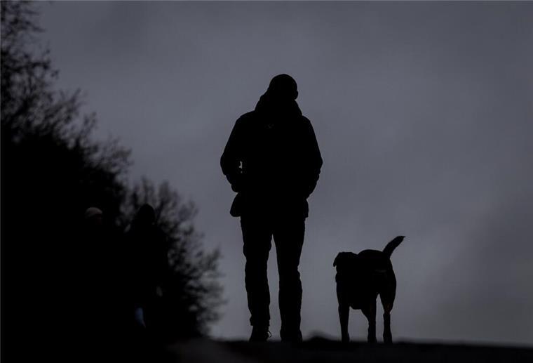 Ein Mann läuft mit seinem Hund bei Nieselregen über den Osterdeich.