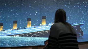 Eine Ausstellungsbesucherin ist von hinten zu sehen. Sie sieht auf einer Leinwand die sinkende "Titanic".