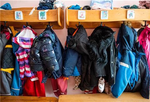 Kein Haken mehr frei: Kinderjacken und Rucksäcke hängen an der Garderobe in einer Kita. 