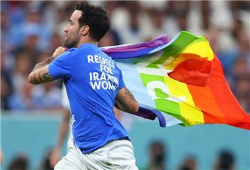 Ein Flitzer mit der Regenbogenflagge und politischen Botschaften zur Ukraine und Iran auf dem T-Shirt läuft über den Rasen